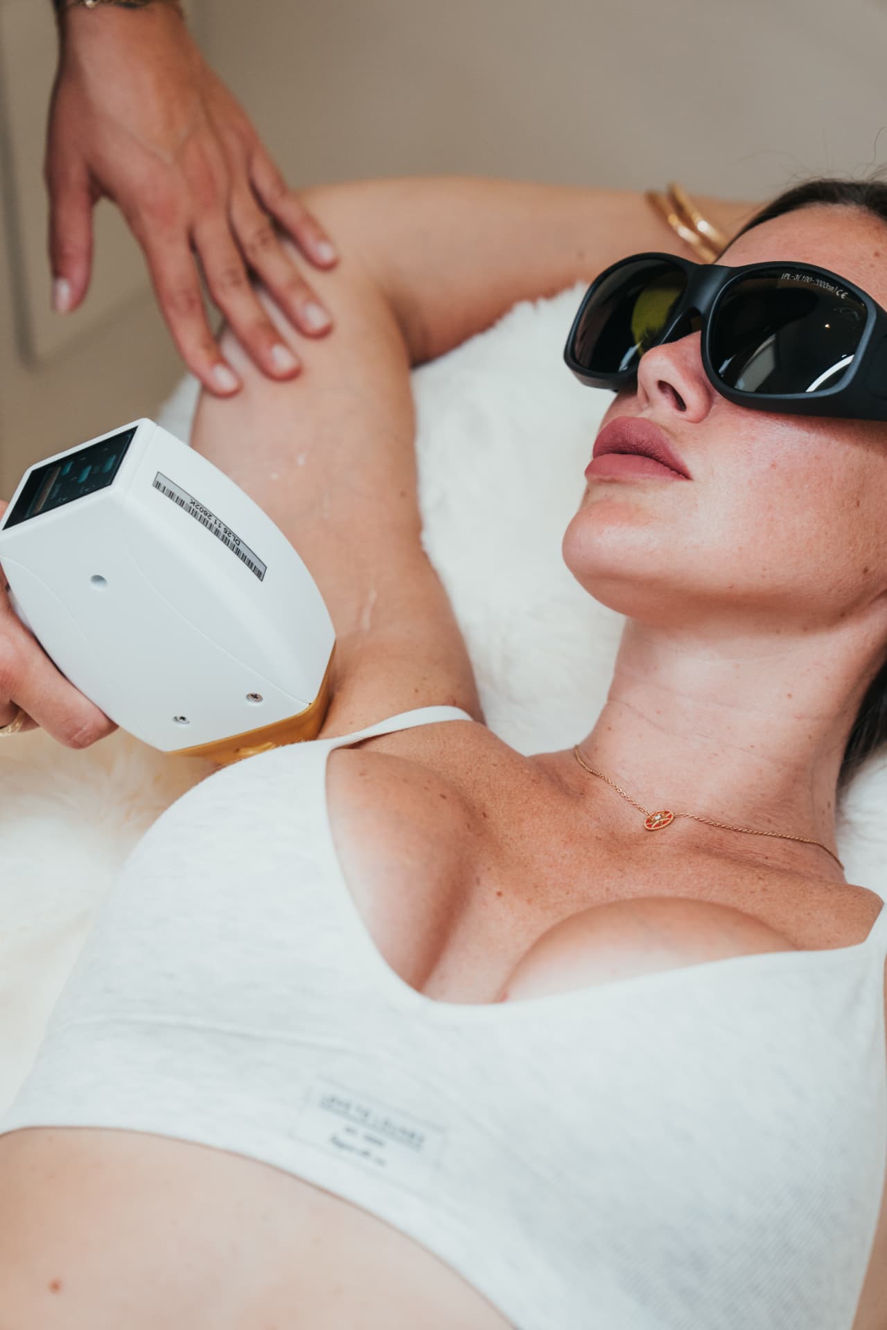 Clienta con gafas de protección durante una sesión de depilación definitiva en axilas