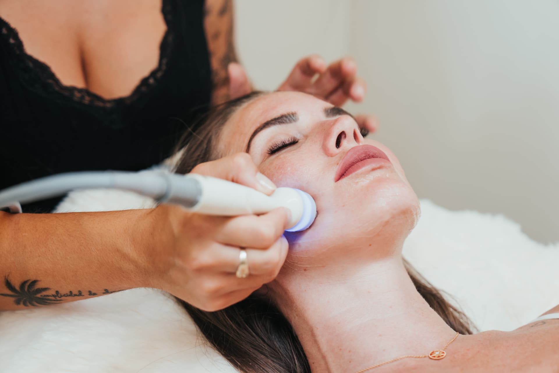 Primer plano de un aparato facial avanzado deslizándose por la mejilla de una clienta